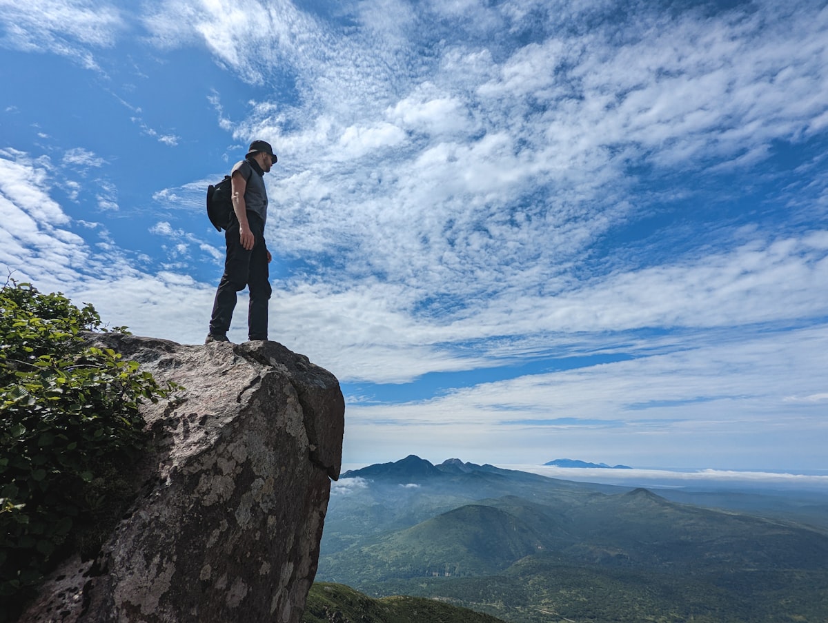Hiker standing on a rocky ledge overlooking a mountain valley, similar to Marsur Rock